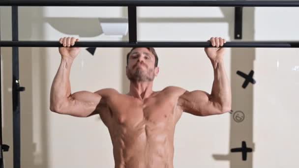 Crossfit athlete doing pull-ups at the gym. Handsome man doing functional training. — Stock videók