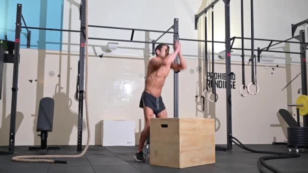 Slow-motion full shot van een fit jonge Kaukasische sportman training alleen doen box jump oefening in de sportschool. — Stockvideo
