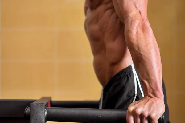 Close up of a Muscular man doing triceps dip on parallel bars in gym. — Stock Photo, Image
