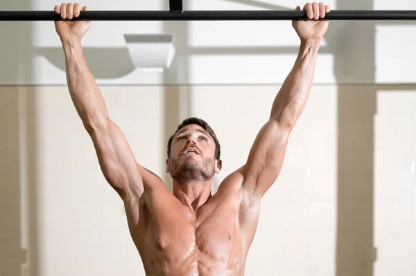 Athlete doing pull-ups at the gym. Handsome man doing functional training. — Stock Photo, Image