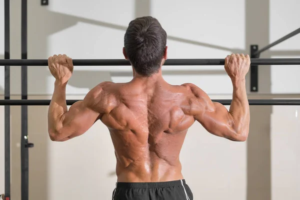 Athlete doing pull-ups at the gym. Handsome man doing functional training. — Stock Photo, Image