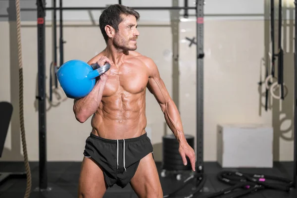 Handsome muscular man lifting heavy kettlebell — Stock Photo, Image
