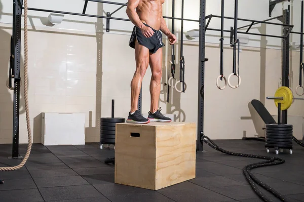 Volledig shot van een fit jonge Kaukasische sportman training alleen doen box jump oefening in de sportschool. — Stockfoto