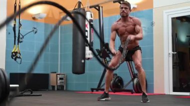 Güçlü kaslı bir adam, fonksiyonel spor salonunda iple çalışıyor..