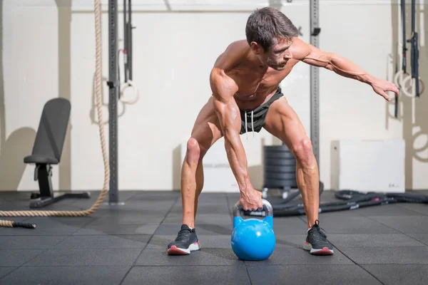 Jonge gespierde man opleiding met kettlebells. — Stockfoto