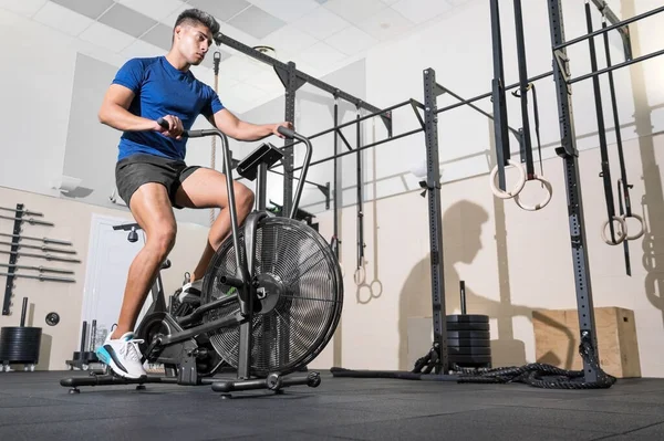 Fit man doet cardiotraining op vaste air bike machine met ventilator in de sportschool. — Stockfoto