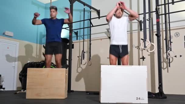 Zwei Fitness-Männer springen in Fitnessstudio auf Fitnessbox. — Stockvideo