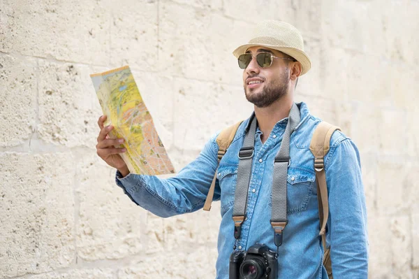 Молодой красивый мужчина с туристической картой, осматривающий городскую улицу. — стоковое фото