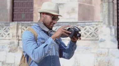Yakışıklı turist dijital kamerayla fotoğrafları kontrol ediyor.