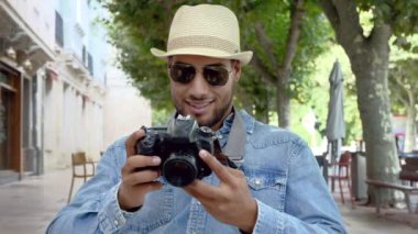 Yakışıklı turist dijital kamerayla fotoğrafları kontrol ediyor.