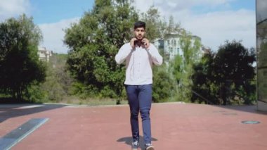 Yakışıklı genç adam gülümsüyor ve sokakta müzik dinliyor..