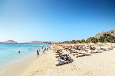 Mykonos, Yunanistan - agoust 23: agoust 23, 2013 tarihinde turistler, şemsiye ve yataklar ile geniş kum plaj. Mykonos Yunanistan'ın en turistik Adaları biridir.