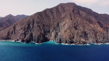 Vallehermoso 'nun engebeli kıyı şeridi, La Gomera, Kanarya Adaları. Sahne dramatik volkanik kayalıkları, derin mavi Atlantik sularını ve okyanusla buluşan yemyeşil tepeleri gösteriyor. Bu uzak ada manzarasının vahşi güzelliğini yakalıyor.. 