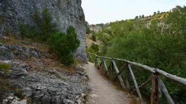 Rio Lobos Kanyonu 'ndaki ahşap korkuluklu dar bir patikayı izleyen ilk kişi kayalık kayalıklardan ve yoğun yeşil bitki örtüsünden Saint Bartolome' un inzivasına doğru yol alıyor.. 