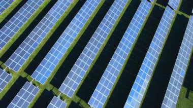 Temiz yenilenebilir enerji üreten, sürdürülebilir enerji üreten, düşük karbonlu bir gelecek için sürdürülebilir enerji üretimi, yeşil teknoloji ve modern altyapı sunan büyük bir güneş paneli çiftliğinin havadan görünüşü. 