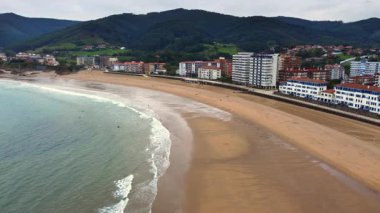 Kuzey İspanya 'daki Bask Bölgesi' nde Bakio plajı ve kıyı kasabasının havadan görüntüsü. Kumlu sahil şeridi, deniz kenarı ve Cantabrian Denizi boyunca yeşil tepeler, insansız hava aracı tarafından ele geçirildi. Yüksek kalite 4k görüntü