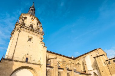 Vitoria-Gasteiz 'deki Santa Maria Katedrali' nin alçak açılı görüntüsü, taştan çan kulesini, Gotik mimarisini ve açık mavi gökyüzünün altındaki tarihi duvarları gösteriyor. Yüksek kalite fotoğraf