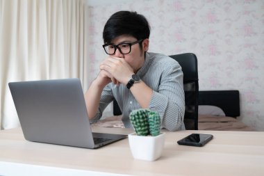 Evde dizüstü bilgisayar ve telefonla çalışan genç iş adamı. Sosyal ağda iletişim kuran, internette bilgi arayan mutlu bir adam..