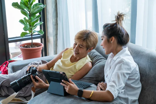 Grandma and grandson play the tablets on the sofa. Exchange knowledge and life stories. relax in living room.