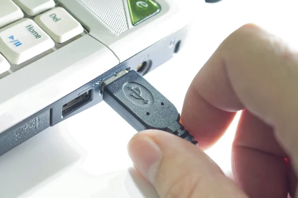 Persona che inserisce il cavo USB nel computer portatile Fotografia Stock