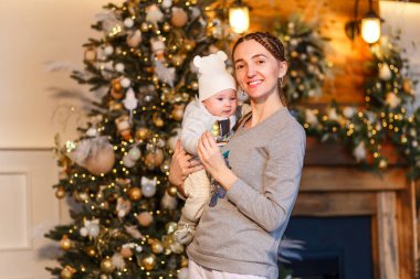 Gülümseyen kadın yeni yıl için altı aylık bebeğini kollarına aldı.