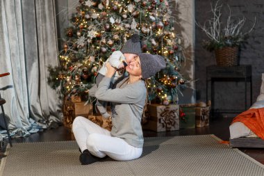 Anne ve kızı Noel ağacının yanında oynuyorlar. Noel için fotoğraf çekimi. Örgü şapkalı insanlar. gri giysi