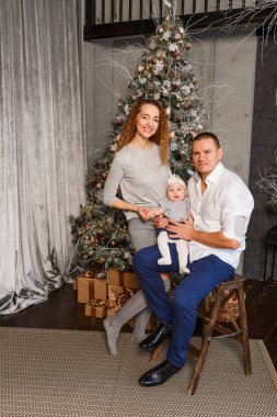 Yeni yıl fotoğraf çekiminde üç kişilik şık bir aile. Noel güzel bir Noel ağacı.