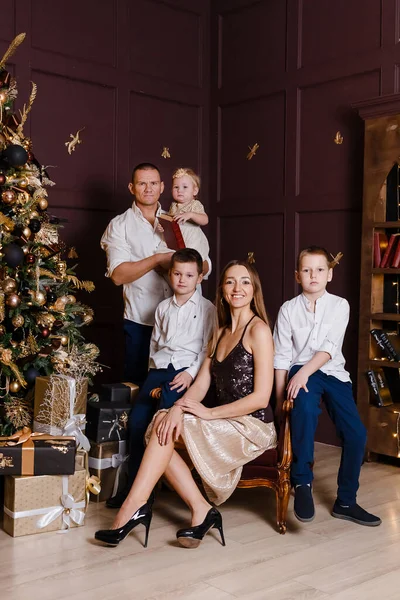 stylish beautiful family in smart clothes at the New Year photo shoot. dark studio design. vertical photo