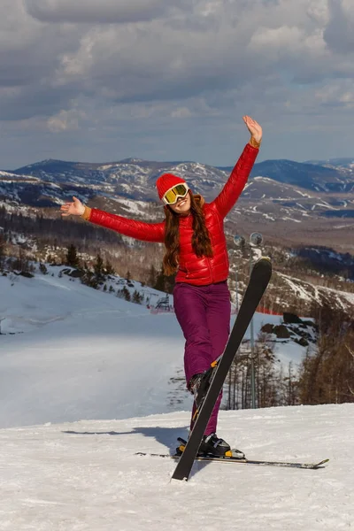 teenage girl in red jacket on skis on mountain mountain in winter