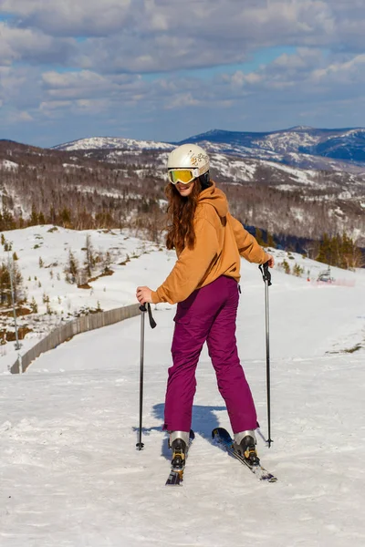 15岁的女孩在滑雪板上笑着回顾冬天的斜坡 — 图库照片