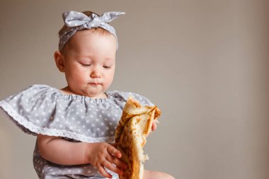 Puantiyeli gri elbiseli küçük kız kreplerle oynuyor. Rus Karnaval Festivali