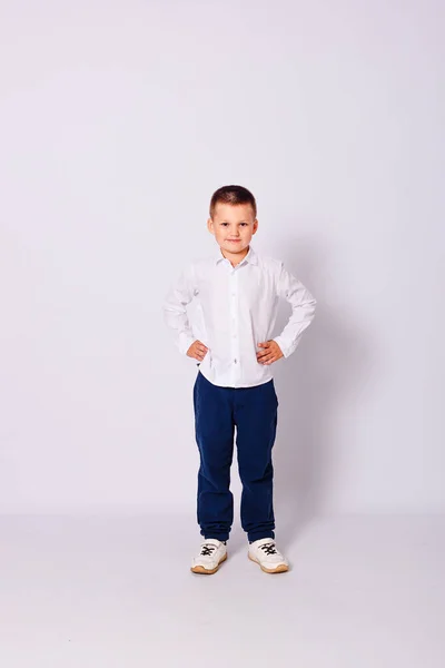 Семилетний Мальчик Синих Брюках Белой Рубашке Стоит Полный Рост Белом — стоковое фото