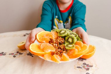 Dokuz yaşında bir çocuk elinde bir tabak meyve tutuyor. Sağlıklı yemek.