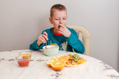 9 yaşındaki bir çocuk masaya oturur ve yulaf ezmesi yer.