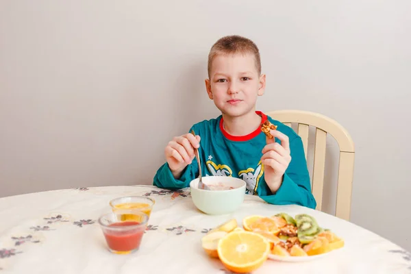 Девятилетний Мальчик Пижаме Сидит Столом Ест Овсянку Фруктами Здоровый Завтрак — стоковое фото