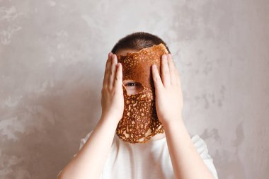 Elinde kreplerle gülen yedi yaşında bir çocuk.