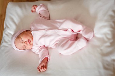 Pembe tulumlu, 5 günlük şirin bir kız, ekose bir elbisenin üzerine uzanıyor ve rüyasında çok yüksekte uzanıyor. yeni doğan fotoğraf çekimi