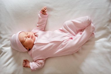 Pembe tulumlu, 5 günlük şirin bir kız, ekose bir elbisenin üzerine uzanıyor ve rüyasında çok yüksekte uzanıyor. yeni doğan fotoğraf çekimi