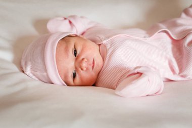 Sadece beyaz bir ekosenin üzerinde gözleri açık doğan bir bebek.