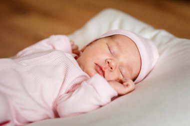 Pembe tulumla bir haftadan az bir süre önce doğmuş bir bebek beyaz bir ekoseyle uyur. Şirin, Küçük Yakından. Yeni doğan fotoğraf çekimi.