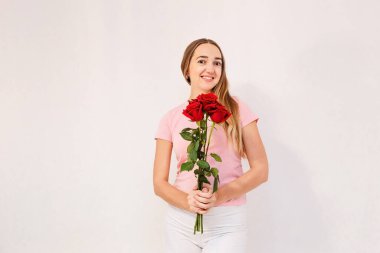 Gülümseyen 30 yaşındaki kadın elinde bir buket kırmızı gül tutuyor.