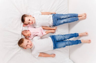 Üç çocuk beyaz bir çarşafta sırtüstü yatıyor. İki ağabeyim ve yeni doğmuş bir kızım var.