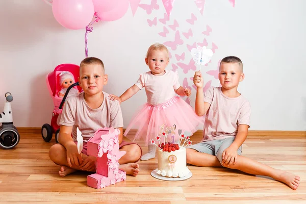 children for birthday sit on the floor of the house with a cake