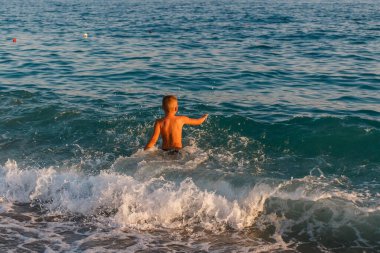Türkiye 'de yedi yaşındaki bronz tenli çocuk denizde koşuyor