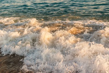 Yazın Türkiye 'de plajda köpüren beyaz dalgalar.
