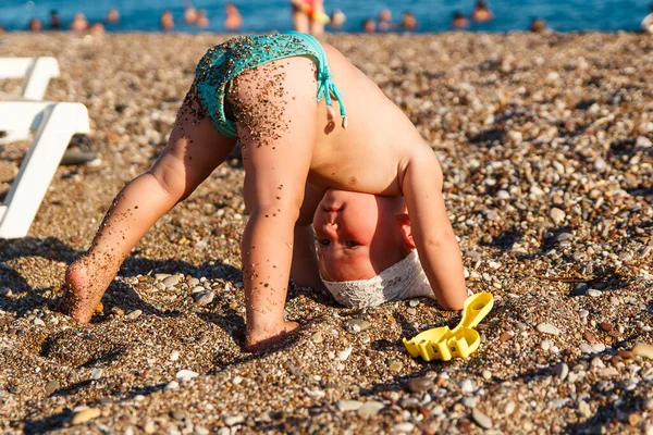 海のそばの子供のヨガ 1歳の日焼けした赤ん坊の女の子は砂の上に裸足で立ち 斜面を下ります — ストック写真