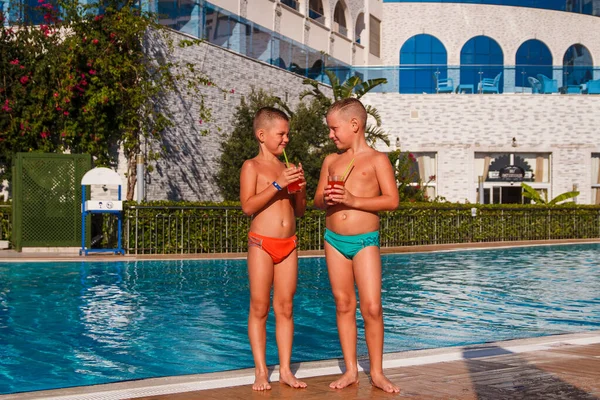 Två Solbrända Korthåriga Pojkar Står Vid Poolen Och Dricker Cocktail — Stockfoto