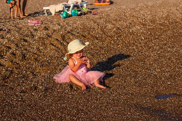 Улыбающаяся Годовалая Девочка Розовой Юбке Соломенной Шляпе Сидит Пляже — стоковое фото
