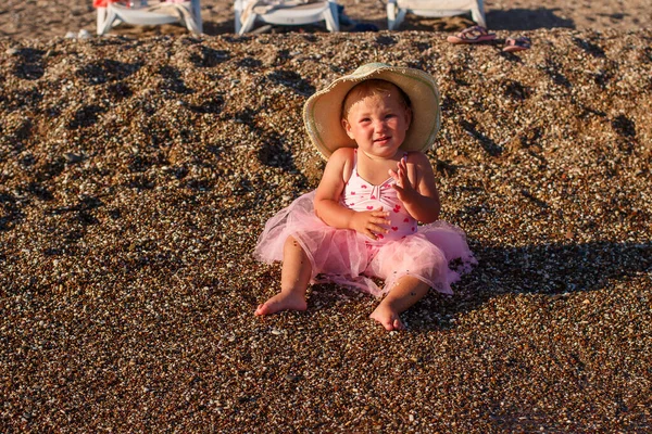 Улыбающаяся Годовалая Девочка Розовой Юбке Соломенной Шляпе Сидит Пляже — стоковое фото