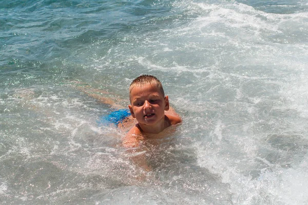 短髪の9歳の男の子が海で泳いで夏に波と遊ぶ — ストック写真